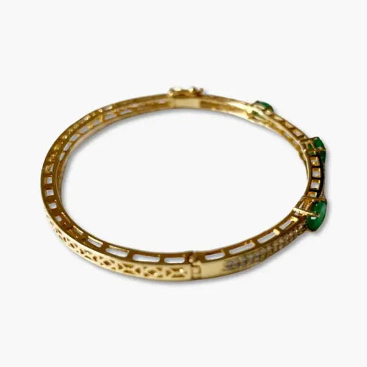 Gold bracelet with green gemstones on a white background