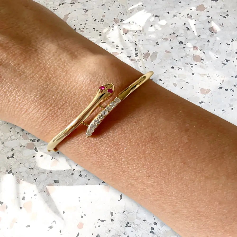 Gold bracelet with red gemstones on a wrist against a light background