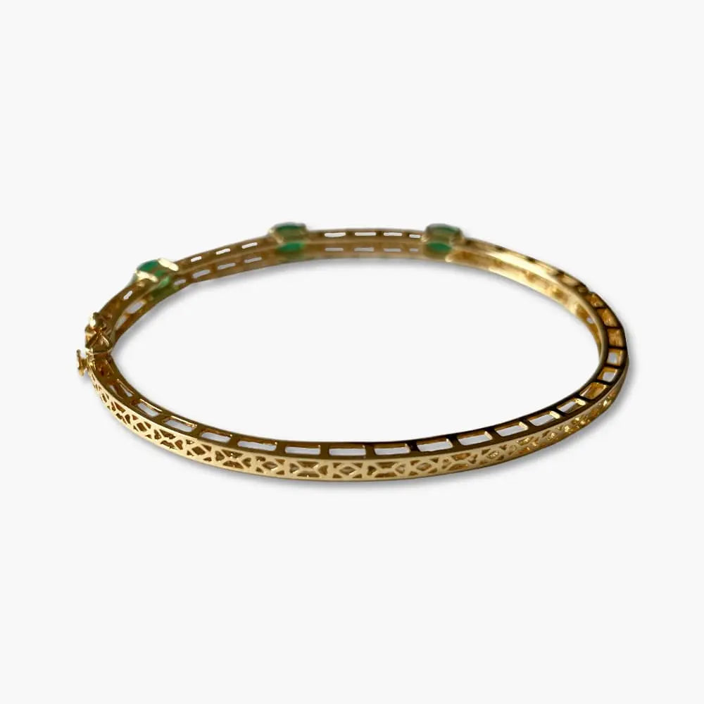 Gold bracelet with green stones on a white background