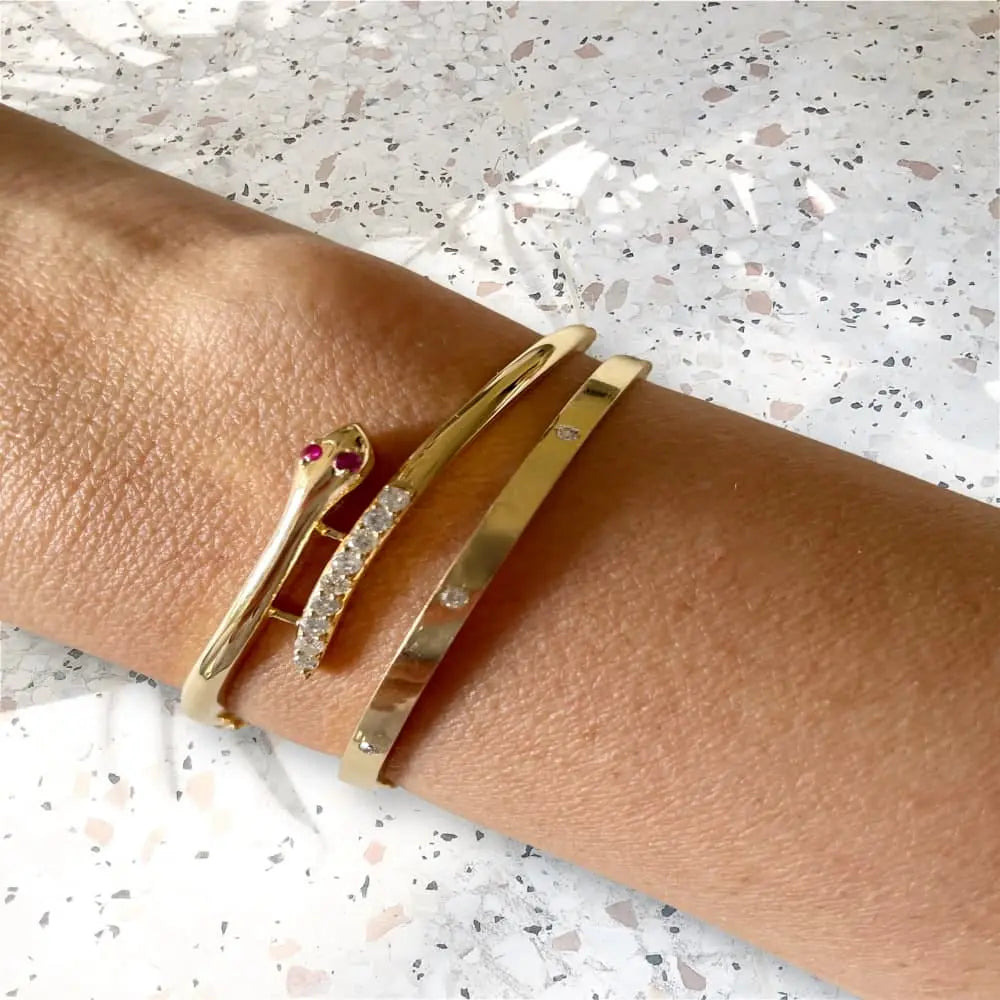 Gold bracelets on a person's wrist with a speckled background
