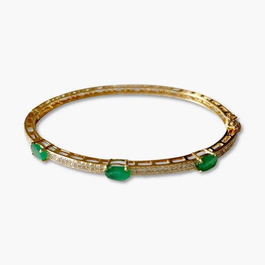 Gold bracelet with green gemstones on a white background