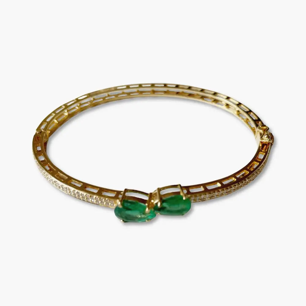 Gold bracelet with green gemstones on a white background
