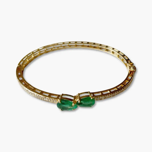 Gold bracelet with green gemstones on a white background