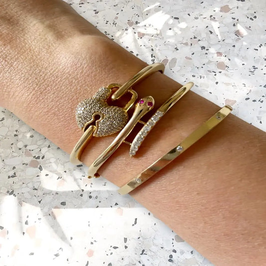 Gold bracelets on a wrist with a speckled gray background