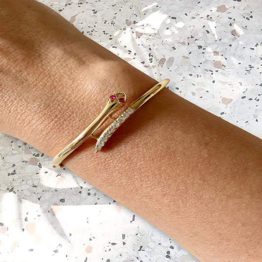 Gold bracelet with red gemstones on a wrist against a light background